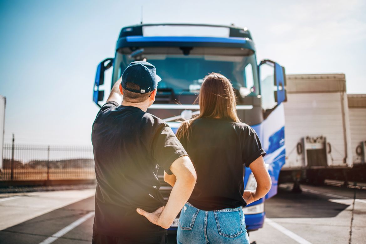 Couple facing backwards and holding documents in front of truck
