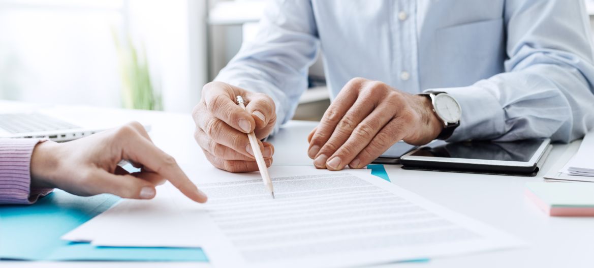 Business people negotiating a contract, they are pointing on a document and discussing together