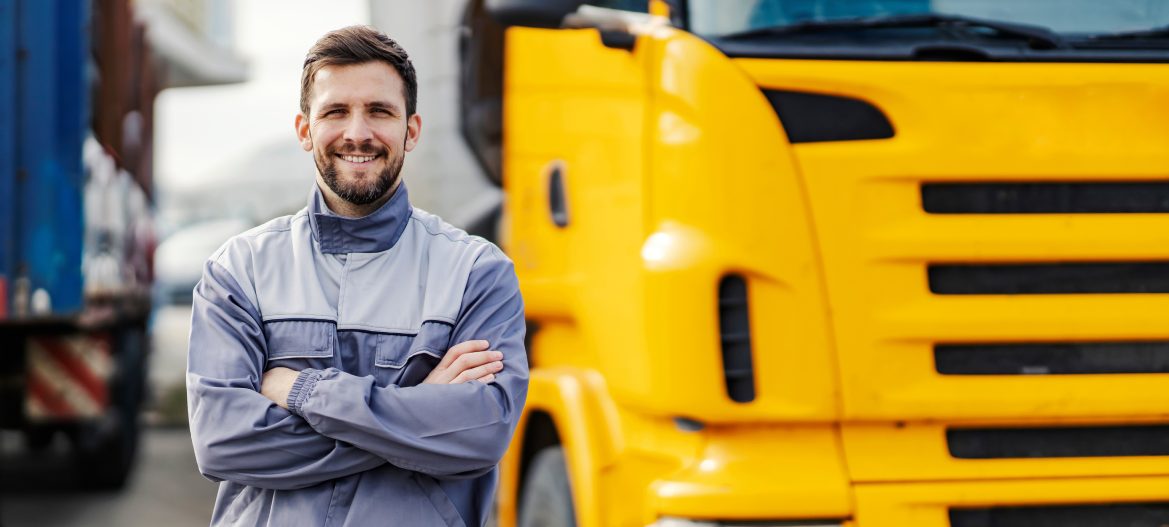 A smiling truck driver posing with trucks.