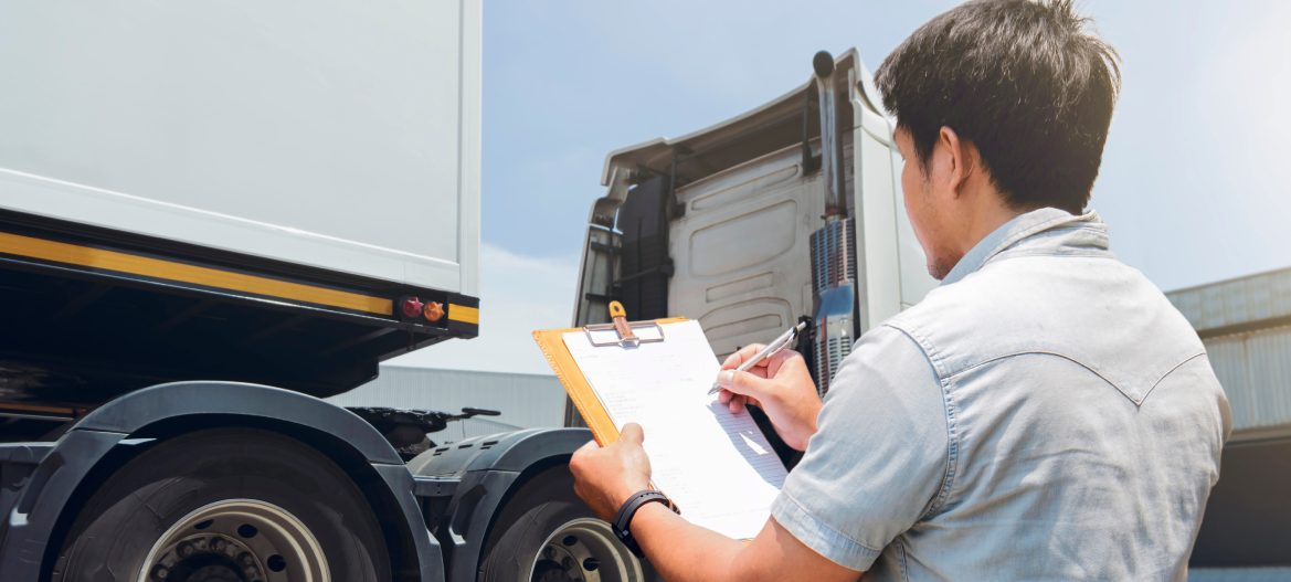 Truck Driver Holding Clipboard is Checking the Truck's Safety Maintenance Checklist. Mechanic Repairman Shop. Inspection of Semi Truck Wheels Tires.Shipping Cargo Freight Truck Transport Logistics.