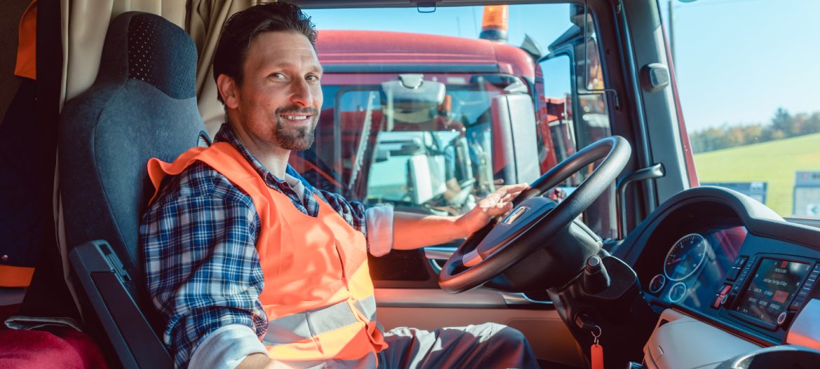 Lorry or truck driver sitting in the cabin of his vehicle driving